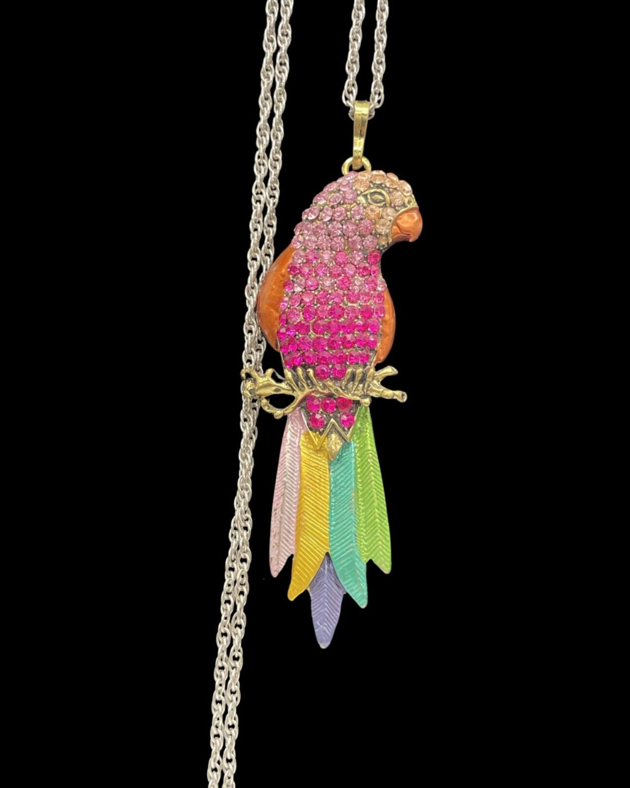 An Elegant Pink Rhinestone Parrot Pendant Necklace with Silver Chain sitting on a chain.